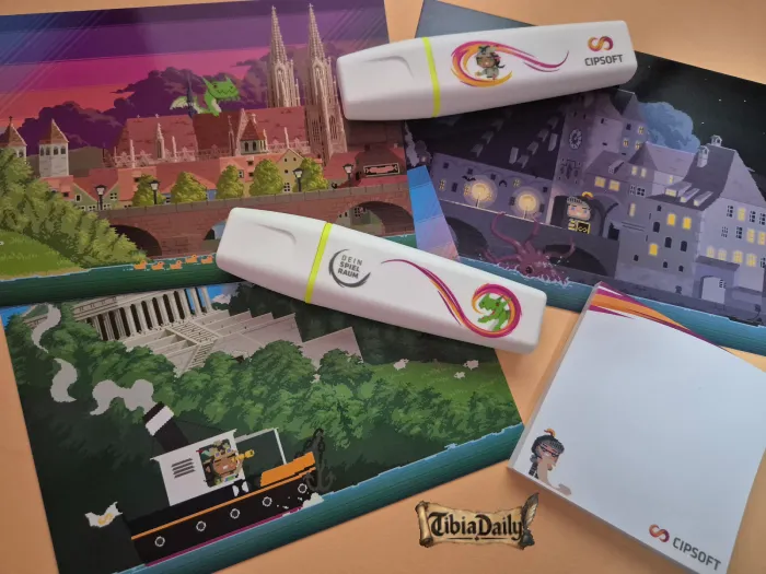 Two CipSoft highlighters and a notepad on pixel-art postcards of Regensburg, one with a green dragon above the cathedral
